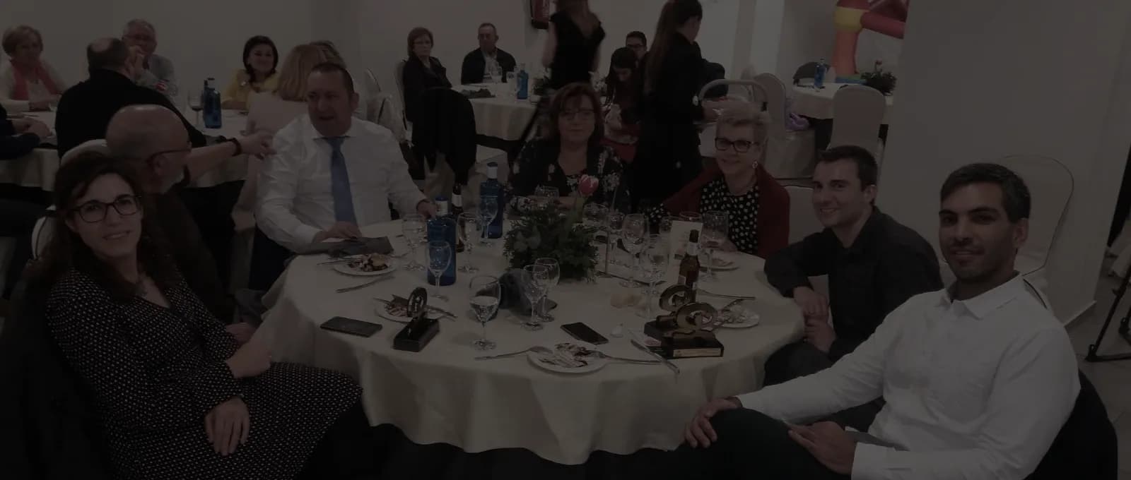 Socios y familias de la asociación sentados alrededor de una mesa en una cena de la asociación